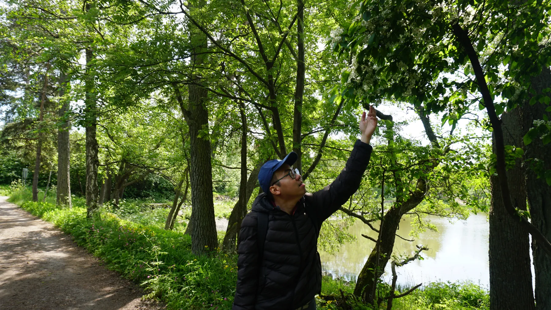 Daniel Nguyen reaching toward a tree while hiking beside a lake