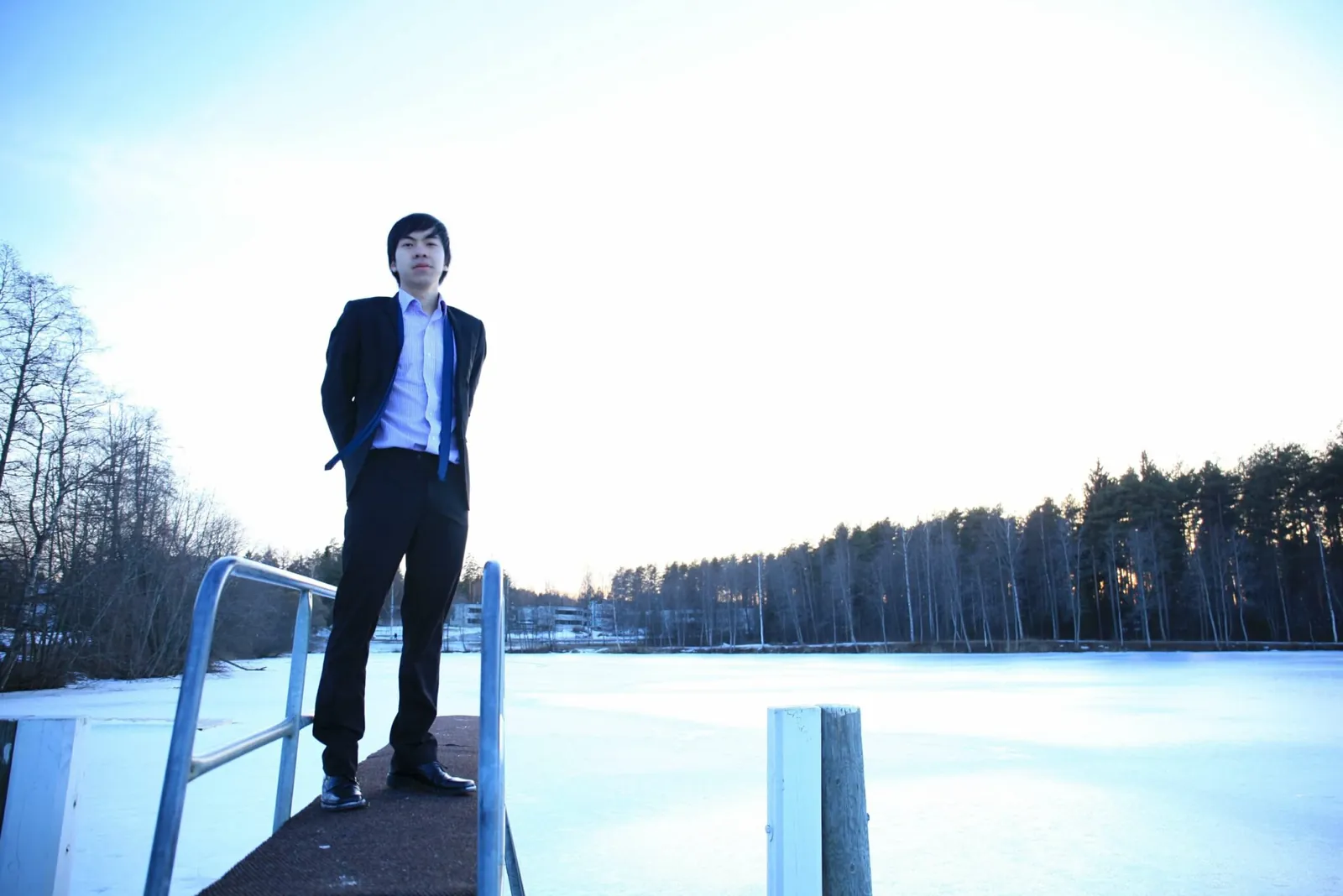 Daniel Nguyen in a suit, standing on a jetty over a frozen lake in Finland